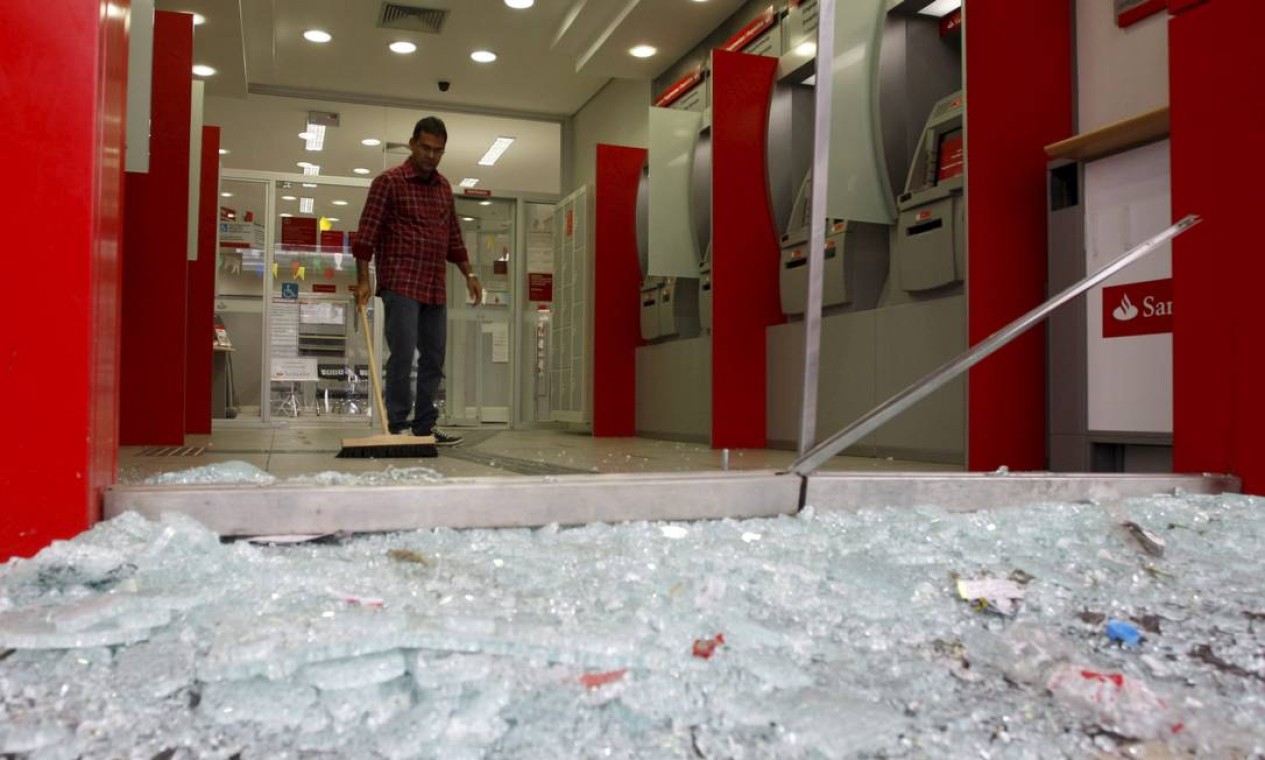 Homem limpa uma agência bancária que teve a vidraça quebrada por manifestantes Foto: Marcos Tristão / Agência O Globo
