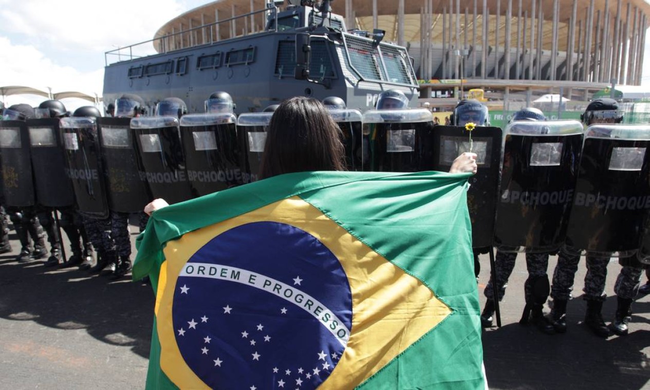 Manifestante com a bandeira do Brasil encara o Batalhão de Choque da Polícia Militar durante o protesto Foto: André Coelho / Agência O Globo