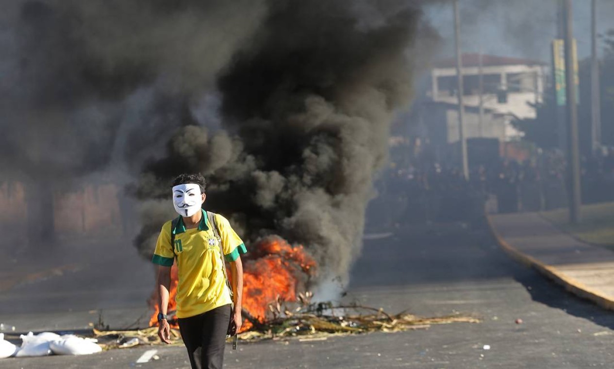 A masked protester walks away from a burning barricade near the Castelao stadium in Fortaleza, Brazil, Wednesday, June 19, 2013. Protesters cut off the main access road to the stadium where Brazil plays Mexico in the Confederations Cup soccer tournament later Wednesday. Beginning as protests against bus fare hikes, the demonstrations have quickly ballooned to include broad middle-class outrage over the failure of governments to provide basic services and ensure public safety. (AP Photo/Andre Penner) Foto: Andre Penner / AP
