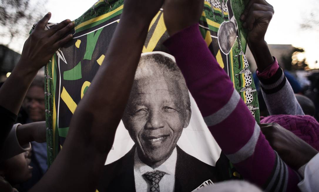 
Sul-africanos levantam bandeira com o rosto de Nelson Mandela Pretória
Foto: MARCO LONGARI / AFP