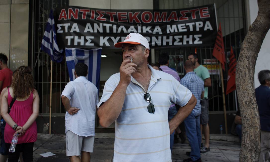 Protesto na porta do local onde autoridades gregas e representantes da troika se reúnem. Na faixa: "Nós resistimos às medidas impopulares do governo" Foto: Kostas Tsironis / AP