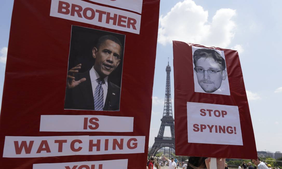 
Manifestantes seguram cartazes com a foto de Barack Obama e do fugitivo americano Edward Snowden Foto: KENZO TRIBOUILLARD / AFP