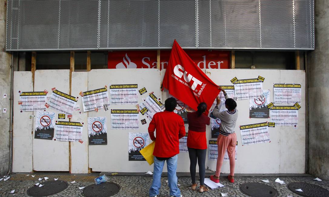 Manifestantes colocam bandeira da CUT na fachada de agência bancária no Centro Foto: Pablo Jacob / Agência O Globo