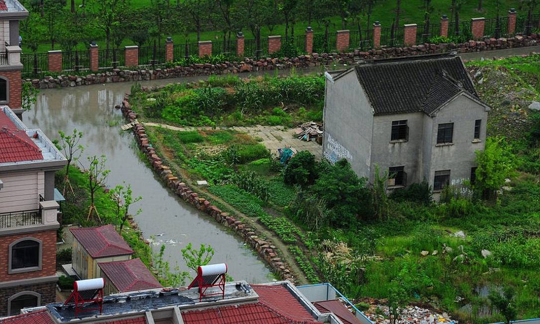 
A casa do chinês de 75 anos foi cercada por um fosso d´água. Zhuang Longdi e sua família precisam atravessar um caminho com água até a cintura para chegar ao imóvel
Foto: Daily Mail
