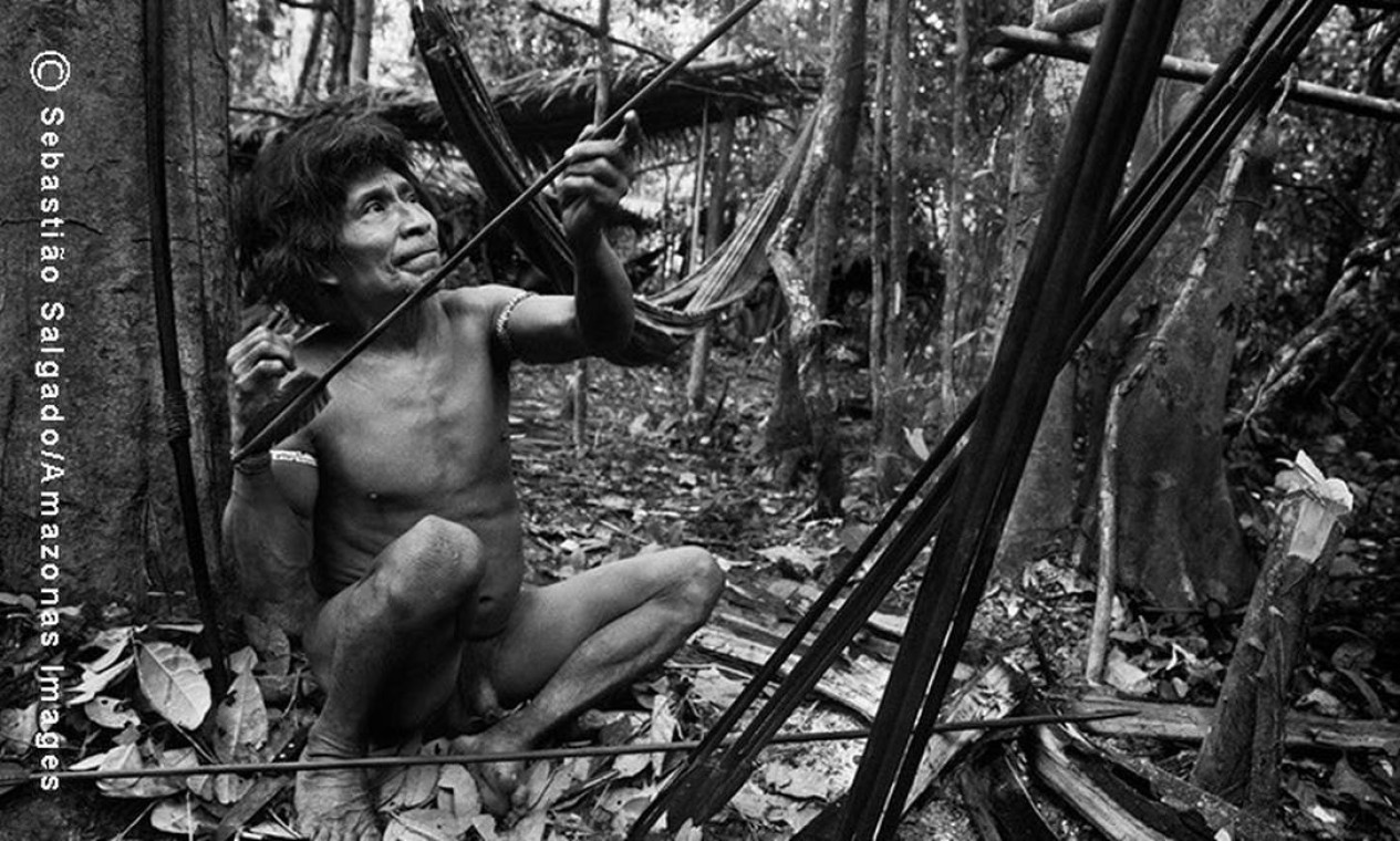 Antes de sair à caça, ao amanhecer, o índio Muturuhum aquece suas flechas para alinhá-las