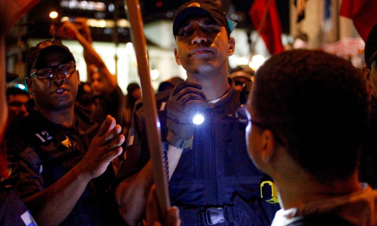 Policial usa lanterna para identificar pessoas no protesto Foto: Pedro Kirilos / Agência O Globo