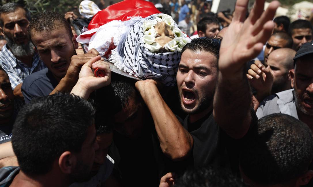 
Palestinos carregam o corpo de um dos três jovens mortos na Cisjordânia
Foto: Majdi Mohammed / AP
