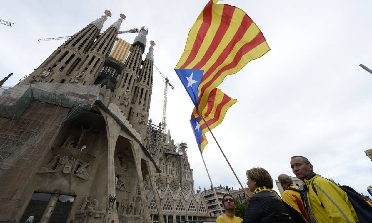 Defensores da independência da Catalunha exibem bandeiras da região em frente à sagrada Família em Barcelona Foto: LLUIS GENE / AFP
