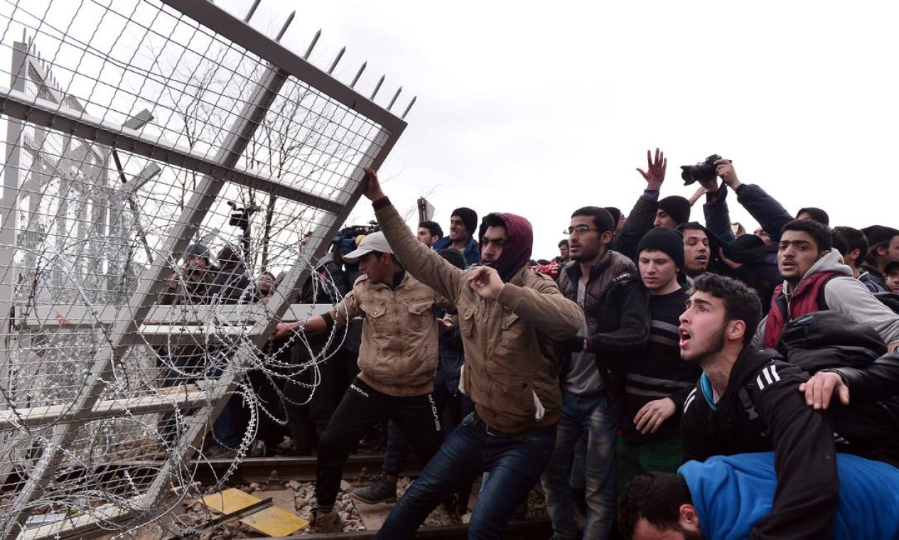 Cerca de 300 refugiados quebram cerca durante protesto na Grécia, próximo à cidade de Idomeni. Atenas tem alertado que o número de pessoas presas na fronteira com a Macedônia pode chegar a 70 mil pessoas no próximo mês. Foto: LOUISA GOULIAMAKI / AFP