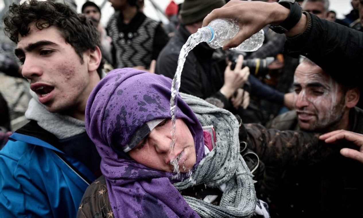 Refugiada joga água no rosto de outra mulher, que passa mal depois de perder o filho em um protesto de cerca de 300 imigrantes contra autoridades da Macedônia Foto: LOUISA GOULIAMAKI / AFP