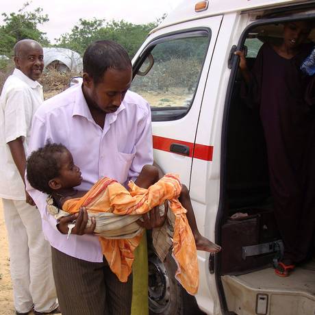 Médico carrega criança subnutrida para receber atendimento em posto de ajuda humanitária no sul de Mogadíscio, na Somália, em 2011 Foto: MUSTAFA ABDI / AFP