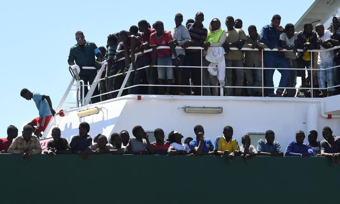 Migrantes aguardando desembarque do navio espanhol Rio Segura no porto de Salerno, Itália