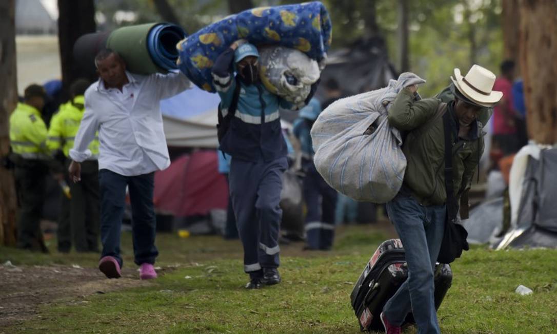 Imigrantes venezuelanos carregam seus pertences ao chegarem a campo humanitário em Bogotá Foto: RAUL ARBOLEDA / AFP 13-11-18