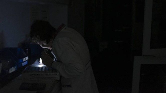 O funcionário de um hospital de Caracas fevisa os diagnósticos de seus pacientes sob a luz de uma lanterna. Foto: Andra Hernández / El País