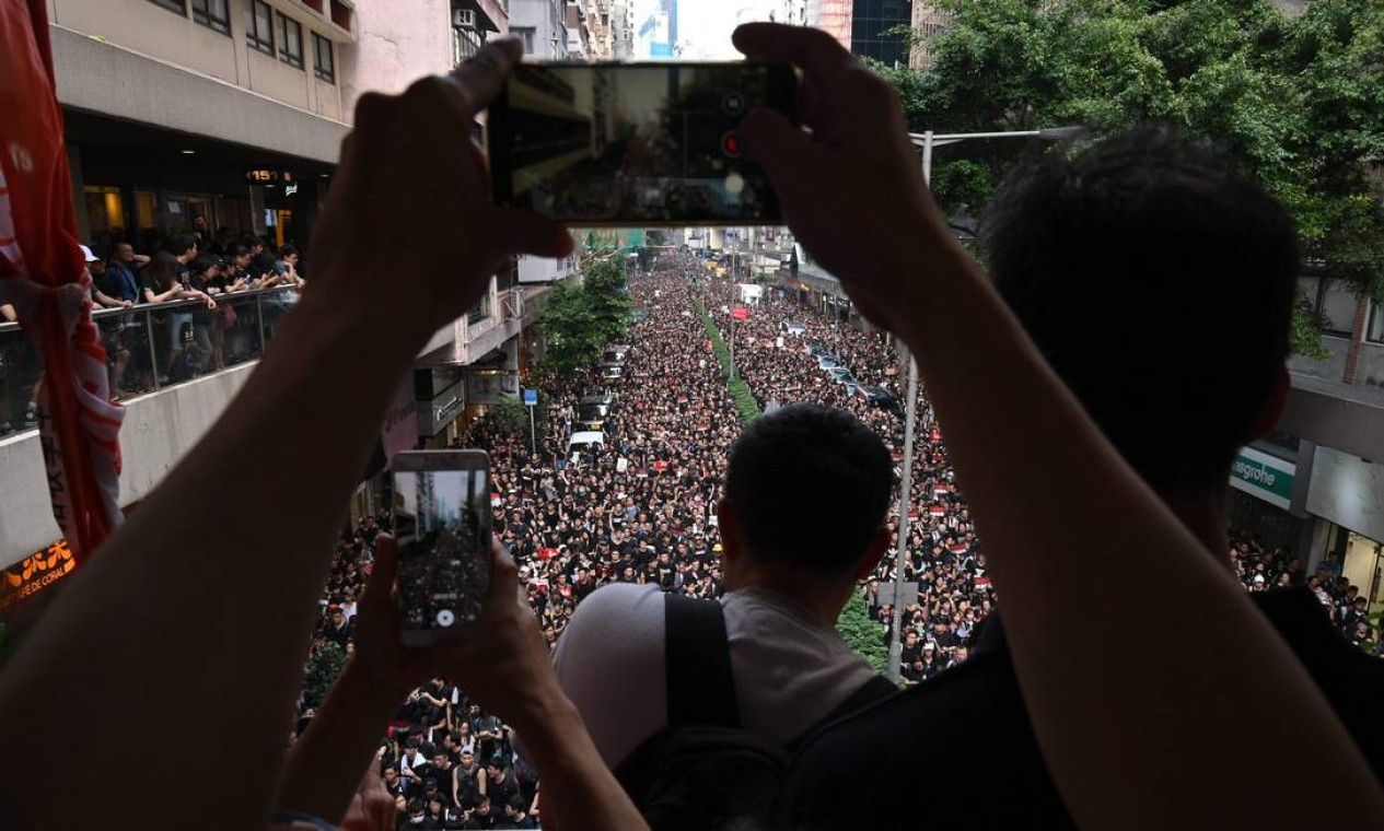 Manifestantes tiram fotos da marcha que reuniu centenas de milhares de pessoas nas ruas de Hong Kong neste domingo, apesar da suspensão da tramitação do projeto da lei de extradição na véspera Foto: HECTOR RETAMAL / AFP