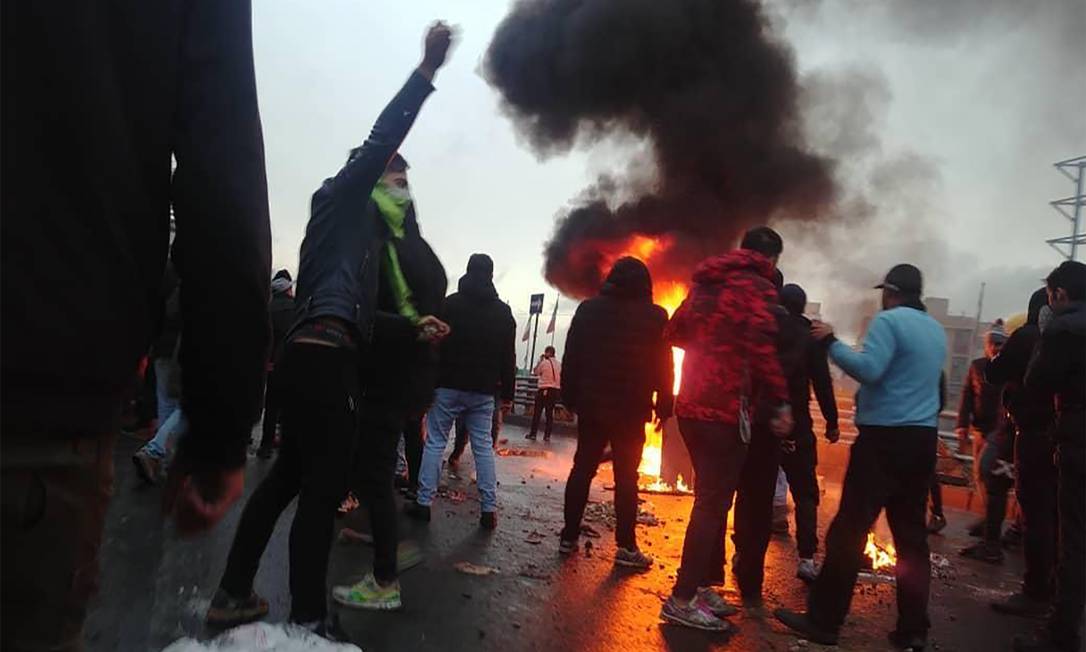 Manifestantes iranianos se reúnem em torno de um incêndio durante uma manifestação contra o aumento dos preços da gasolina na capital Teerã, em 16 de novembro de 2019 Foto: - / AFP