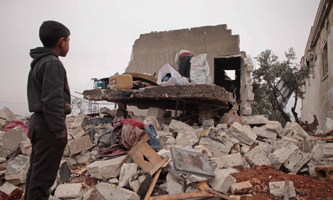 Menino sírio olha para os escombros da casa onde morava com sua família deslocada na vila de Kafr Taal, na zona rural ocidental de Aleppo, após um bombardeio pró-regime. Guerra iniciada em 2011 ainda deixa marcas na Síria. 20/01/2020 Foto: AAREF WATAD / AFP