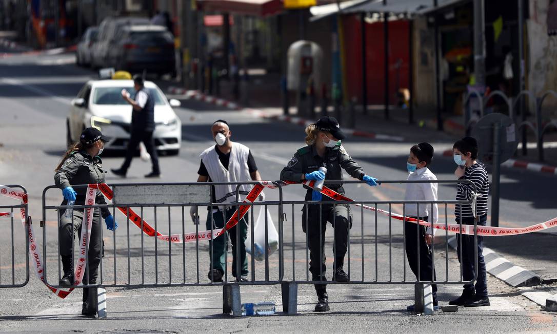 Policiais conversam com moradores locais na entrada de Bnei Brak: Israel impõe bloqueio à cidada seriamente afetada pelo coronavírus Foto: AMMAR AWAD / REUTERS