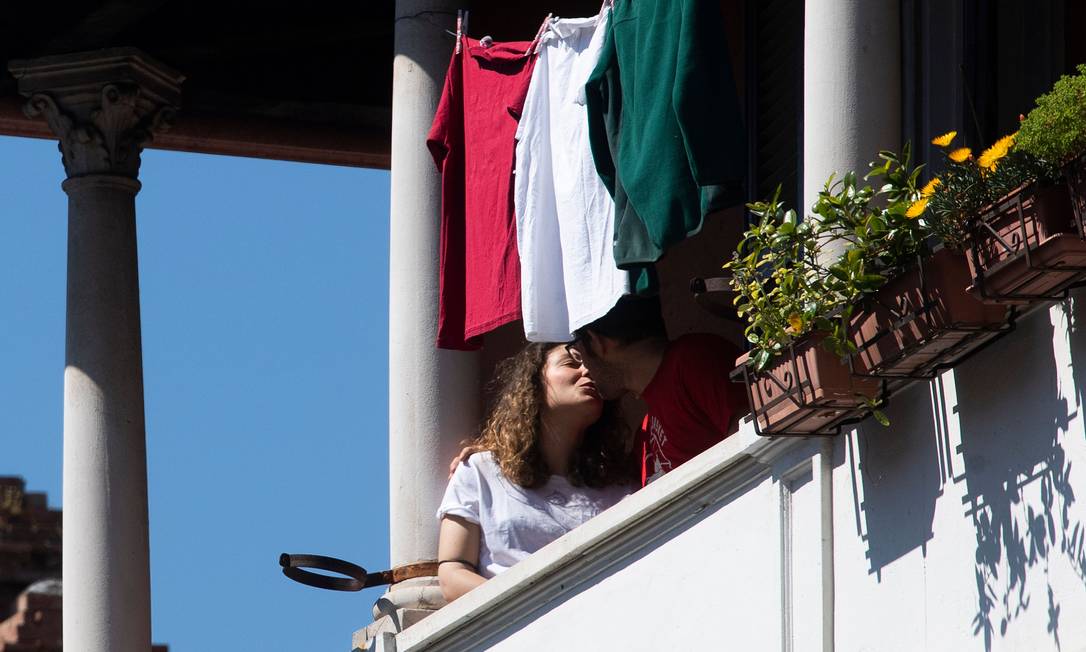 Moradores do bairro de Garbatella em Roma se beijam no momento em que italianos foram para as janelas e balcões cantar "Bella Ciao", hino da Resistência Foto: TIZIANA FABI / AFP