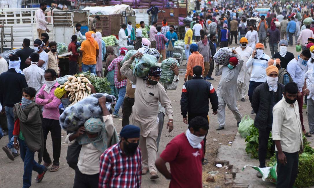 Indianos passam por uma rua: países emergentes enfrentam tripla ameaça, a própria pandemia, queda no comércio e fuga de capitais, disse Tooze Foto: NARINDER NANU / AFP