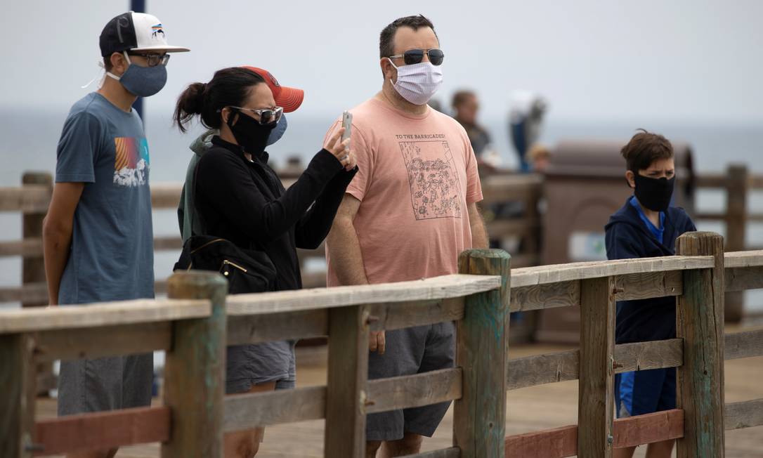 Pessoas usam máscaras enquanto caminham em píer, em Oceanside, na Califórnia: estado americano foi um dos que registraram ameaças a agentes da saúde pública. Foto: MIKE BLAKE / REUTERS