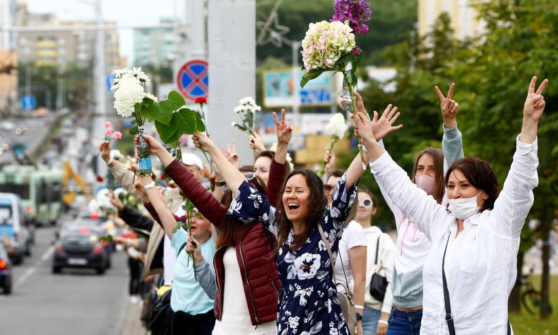 Mulheres seguram flores na beira de rodovia em protesto na Bielorrússia Foto: VASILY FEDOSENKO / REUTERS