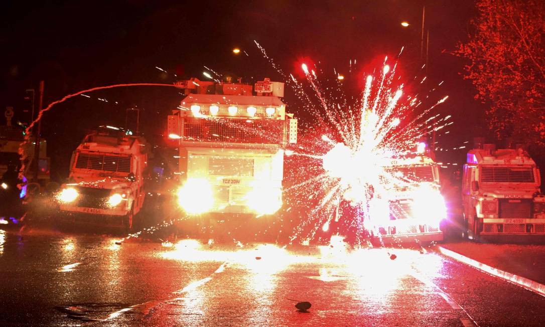 Fogos de artifício lançados por jovens nacionalistas contra caminhões da polícia explodem em Belfast Foto: PAUL FAITH / AFP