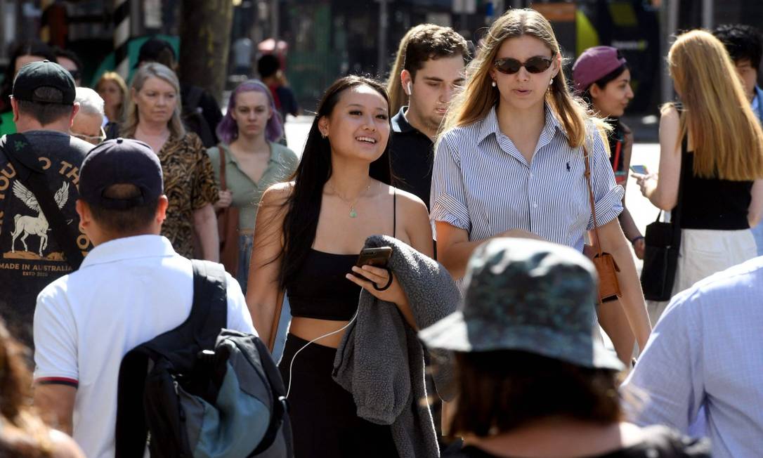 Pessoas caminham pelo distrito comercial de Melbourne, na Austrália, onde o vírus está controlado e não é preciso usar máscaras Foto: WILLIAM WEST / AFP