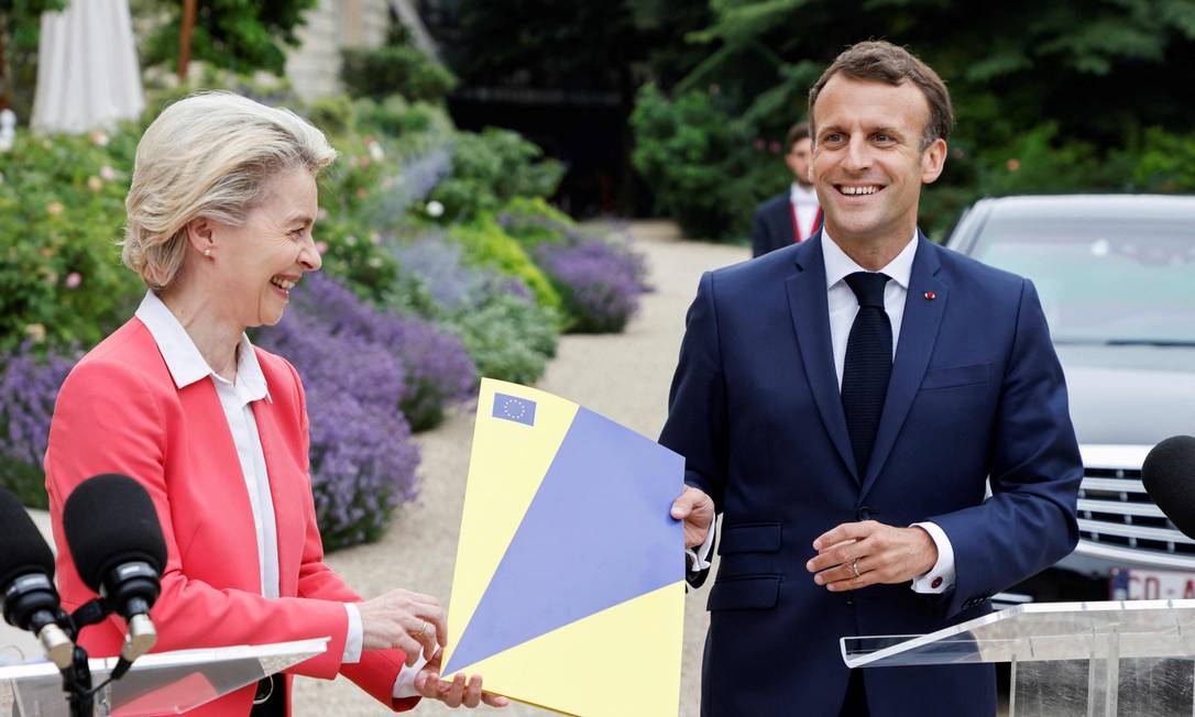 A presidente da Comissão Europeia, Ursula von der Leyen, entrega uma pasta que simboliza o plano de resgate ao presidente da França, Emmanuel Macron Foto: LUDOVIC MARIN / AFP