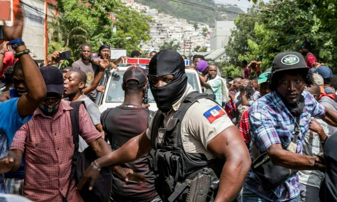 Multidão comemora enquanto carro de polícia se aproxima da delegacia onde suspeitos da morte do presidente haitiano, Jovenel Moïse, estão detidos Foto: VALERIE BAERISWYL / AFP