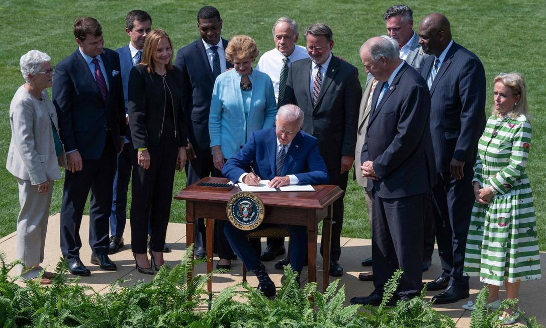 O presidente americano Joe Biden assina a ordem executiva no jardim da Casa Branca, rodeado por executivos da indústria automobilística americana Foto: JIM WATSON / AFP