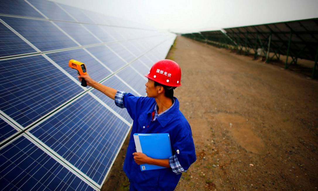 Trabalhador inspeciona paines solares em Dunhuang, a 950km a noroeste de Lanzhou, em Gansu, na China Foto: Carlos Barria / REUTERS 16-9-13