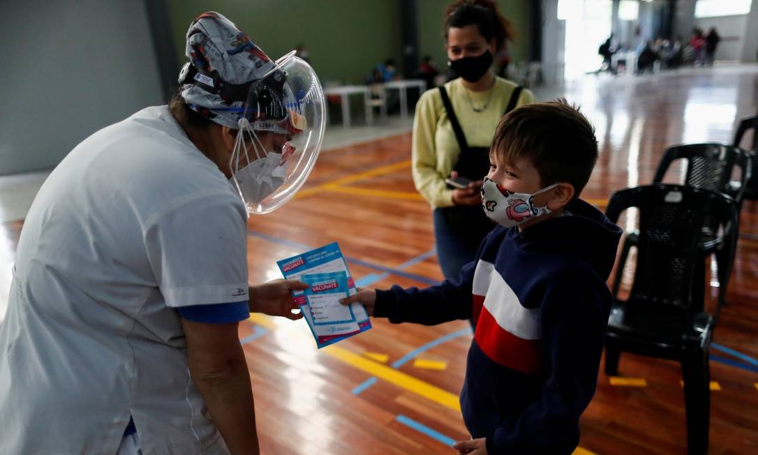 Profissional da saúde fala com menino de 7 anos após ele receber a vacina contra o coronavírus em Buenos Aires Foto: AGUSTIN MARCARIAN / Reuters 15-10-21