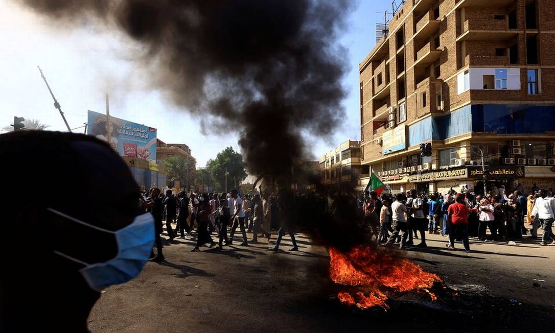 Pneus queimando no chão enquanto os manifestantes marcham durante uma manifestação contra o regime militar, após o golpe do mês passado em Cartum do Norte, no Sudão. Foto: Mohamed Nureldin Abdallah / REUTERS