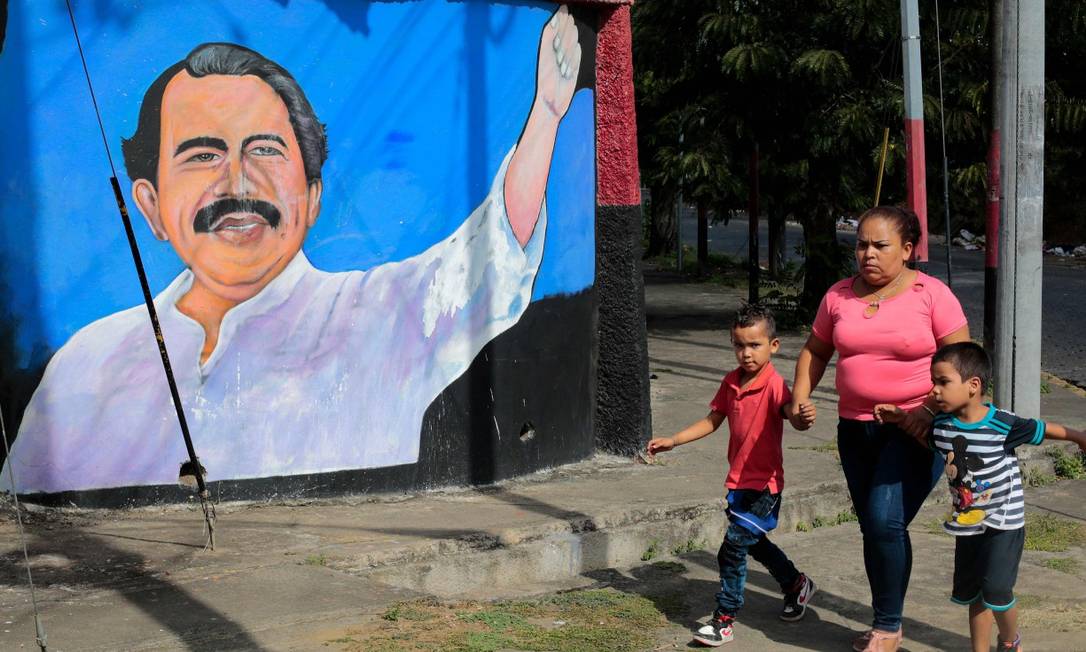 Mulher caminha com crianças em frente a mural de Daniel Ortega em Manágua nesta quarta-feira Foto: OSWALDO RIVAS / AFP