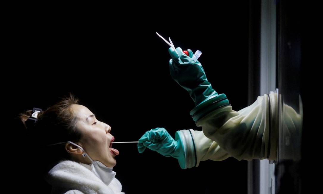 Mulher faz teste de swab para detectar possível infecção por Covid-19 nesta segunda-feira em Pequim Foto: THOMAS PETER / REUTERS