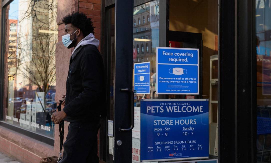 Homem usando máscara deixa loja em Nova York com adesivo na porta indicando a obrigatoriedade do apetrecho Foto: ANGELA WEISS / AFP