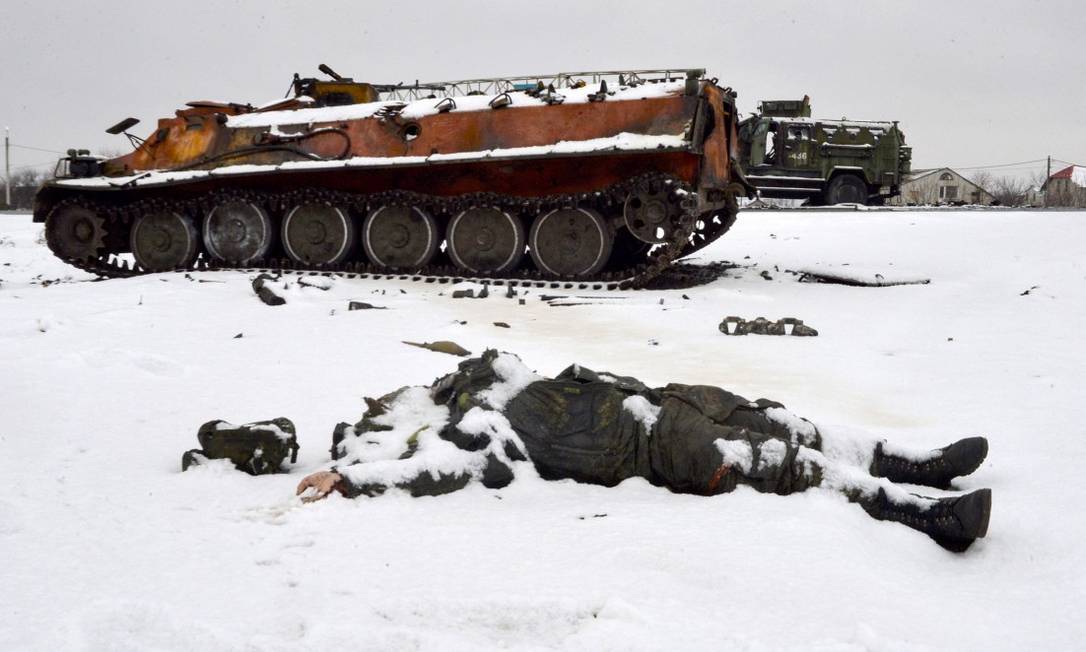 O corpo de um soldado do Exército russo perto de um veículo militar destruído em uma das estradas nos arredores de Kharkiv, a segunda maior cidade da Ucrânia, nesta sexta-feira Foto: SERGEY BOBOK / AFP