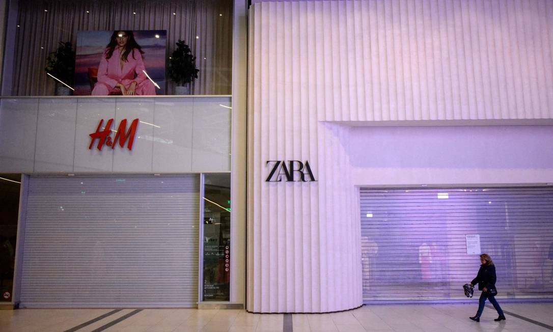 Uma mulher anda em frente a lojas da Zara e da H&M fechadas devido às sanções em um shoppinng em Moscou Foto: KIRILL KUDRYAVTSEV / AFP