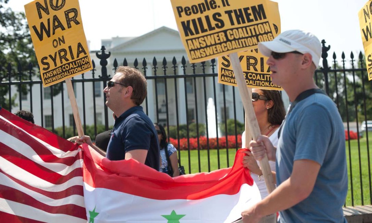 "Sem guerra na Síria". Manifestantes carregam cartazes, em frente à Casa Branca, em protesto contra intervenção militar americana na Síria Foto: NICHOLAS KAMM / AFP