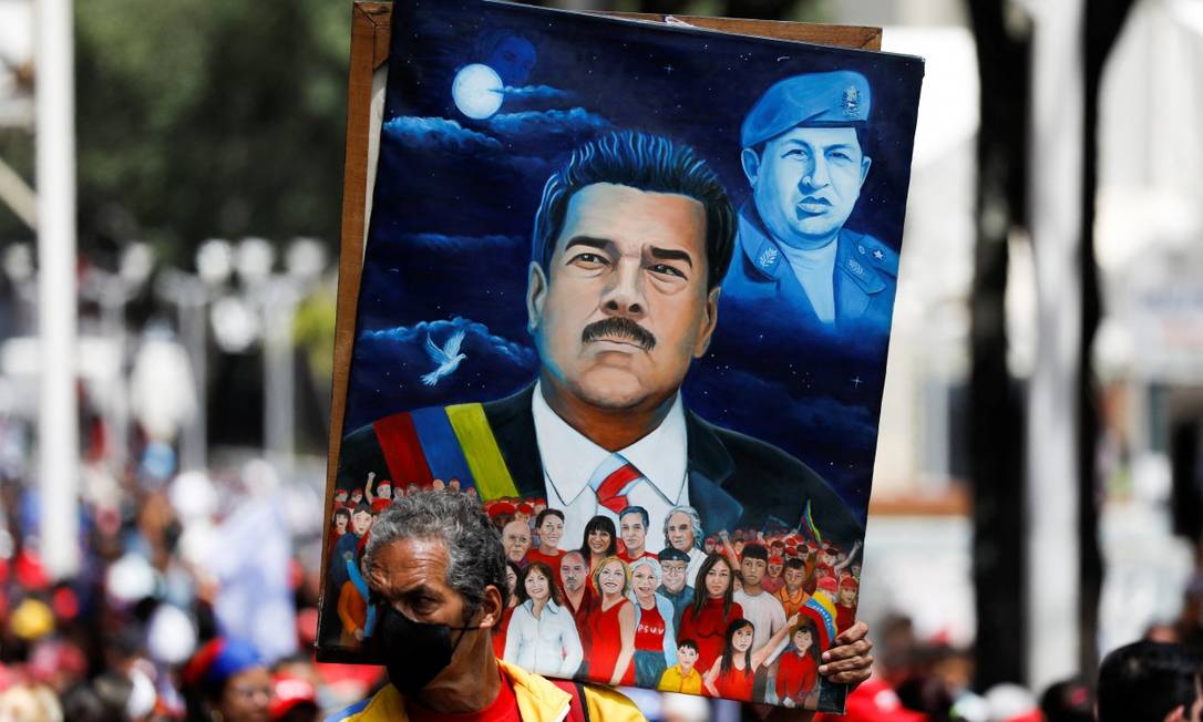 Culto. Cartaz com a imagem do presidente da Venezuela, Nicolás Maduro, e o ex-presidente Hugo Chavez ao fundo: Lula e Bolsonaro se dividem sobre o assunto Foto: LEONARDO FERNANDEZ VILORIA / REUTERS / 13/04/2022