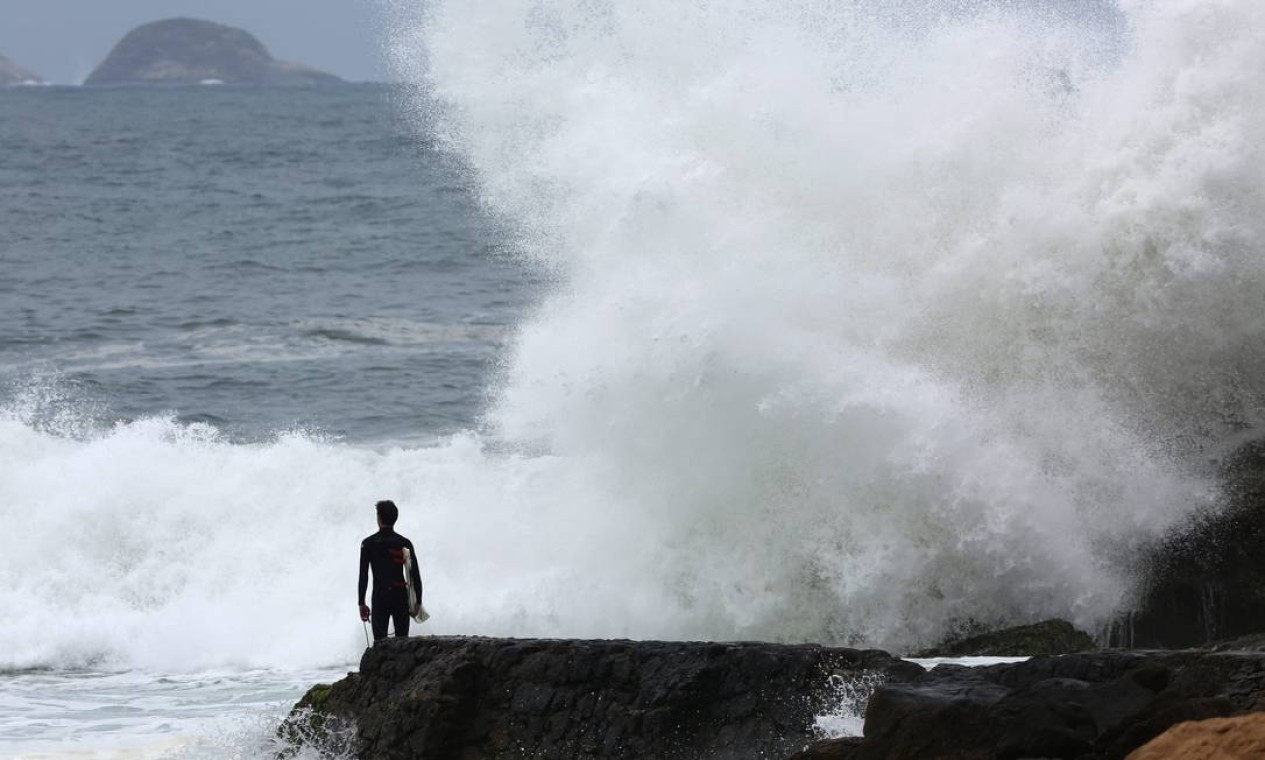 Surfista observa as ondas que batem na pedra na Praia do Leblon: se atreverá a entrar no mar? Foto: Custódio Coimbra / Agência O Globo