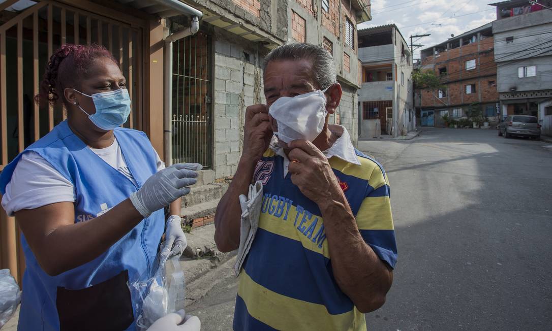 Agente de saúde orienta homem sobre o uso de máscaras em São Paulo: obrigatoriedade foi suspensa ao ar livre no estado (13/08/2020). Foto: Edilson Dantas / Agência O Globo